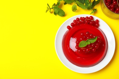 Photo of Delicious fresh red jelly with berries and mint on yellow background, flat lay. Space for text