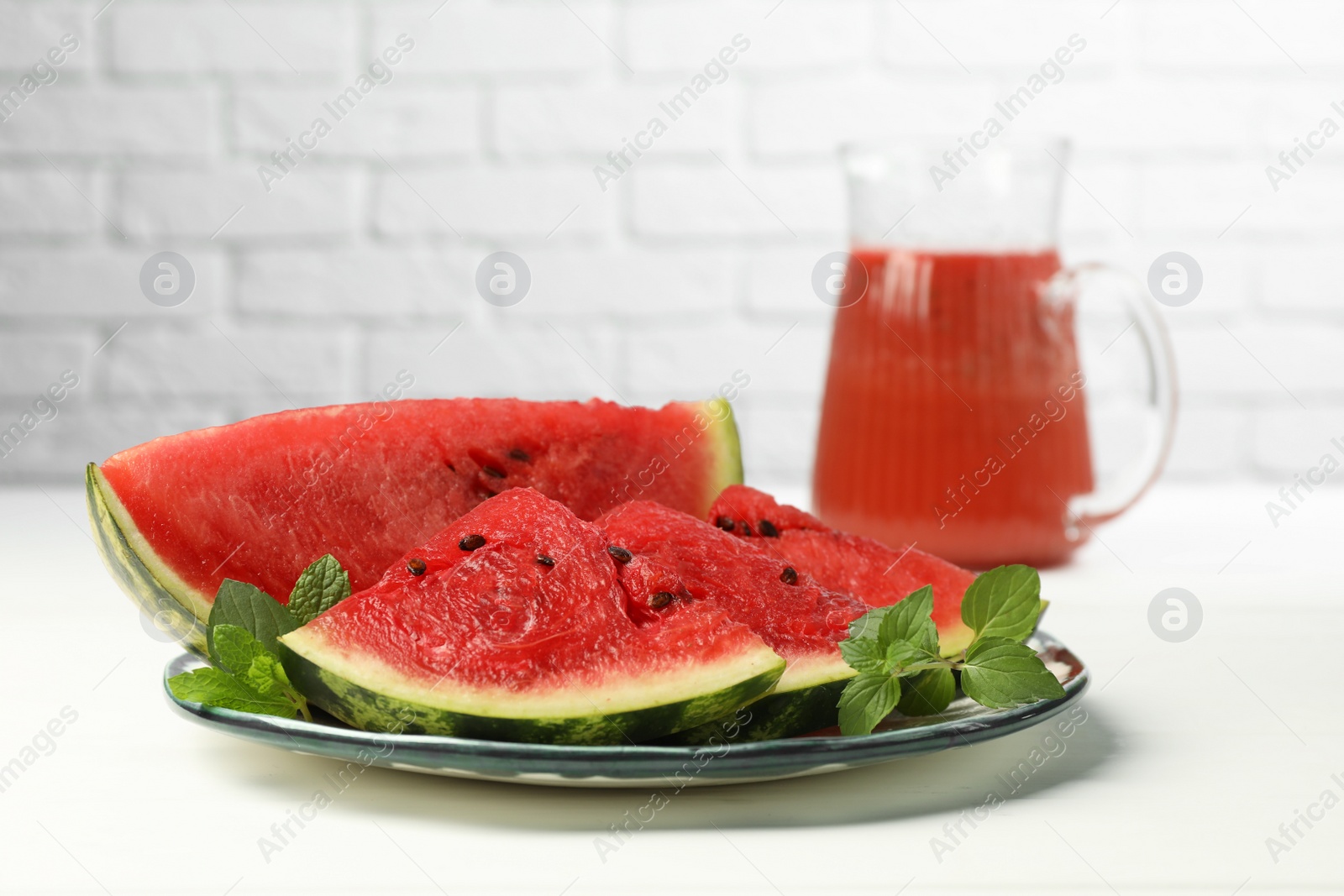 Photo of Plate with slices of juicy watermelon on white wooden table