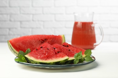 Plate with slices of juicy watermelon on white wooden table