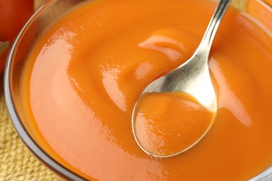 Taking delicious persimmon jam with spoon from bowl, closeup