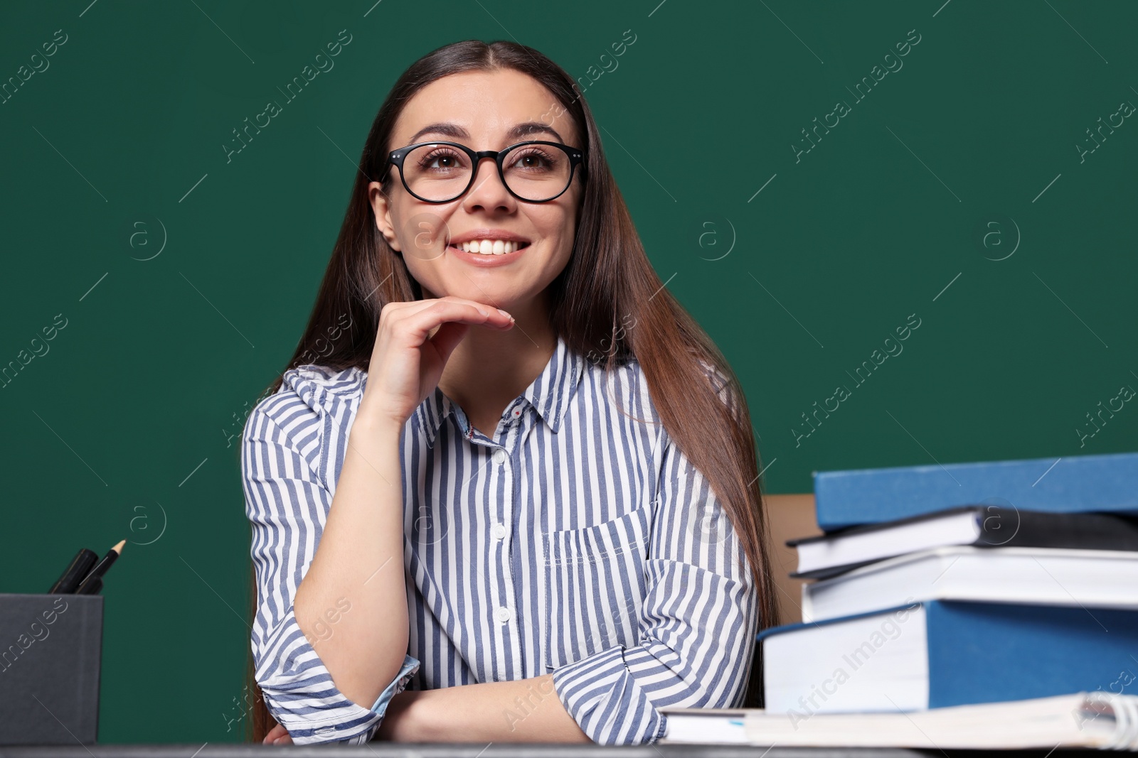 Photo of Portrait of young teacher at table against green background