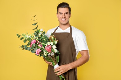 Photo of Florist with beautiful bouquet on yellow background