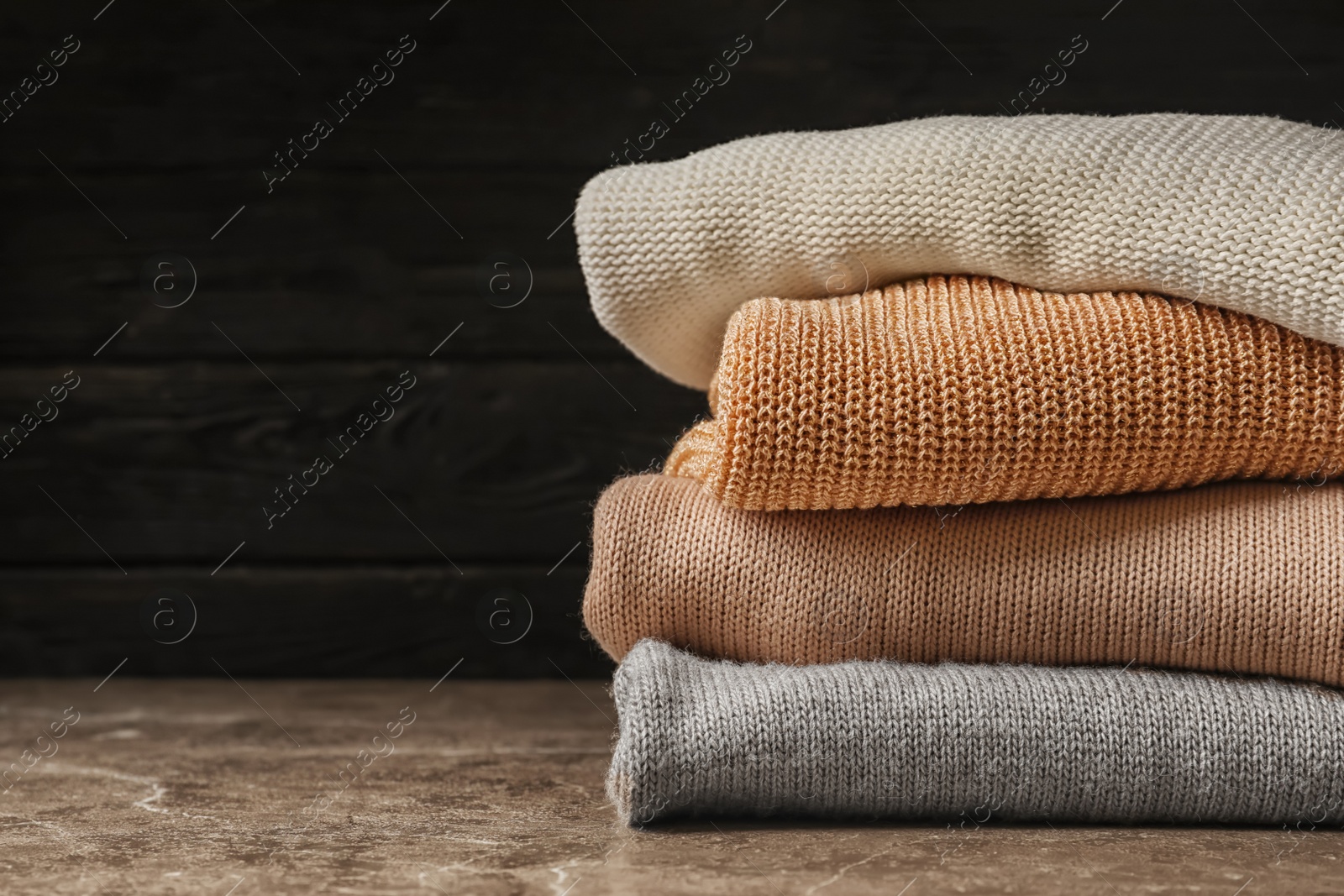 Photo of Stack of warm knitted clothes on table