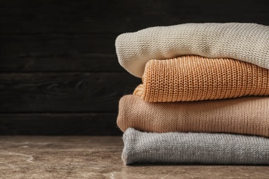 Photo of Stack of warm knitted clothes on table