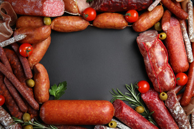 Frame made of different sausages on black background, flat lay. Space for text