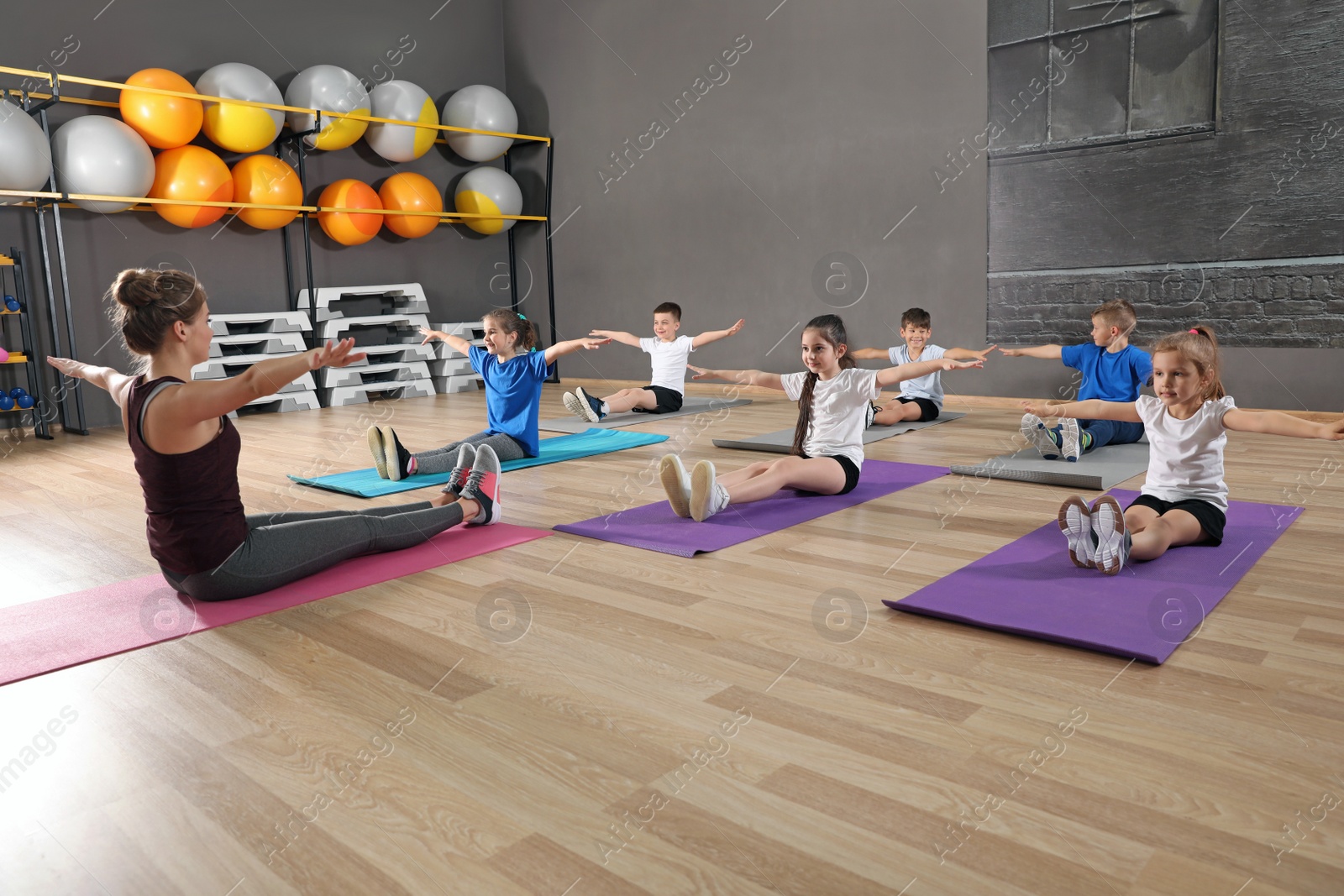 Photo of Cute little children and trainer doing physical exercise in school gym. Healthy lifestyle