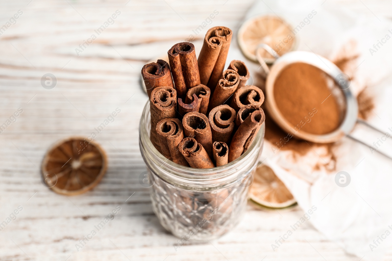 Photo of Jar with aromatic cinnamon sticks on wooden background