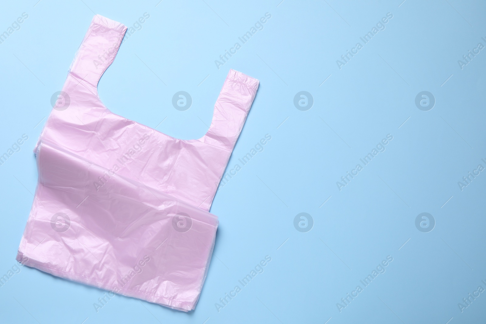Photo of Pack of plastic bags on light blue background, top view. Space for text