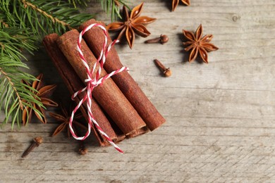 Different spices and fir branches on wooden table, flat lay. Space for text