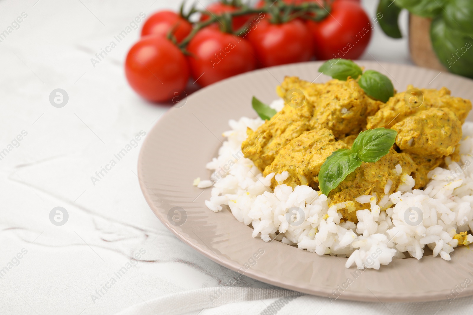 Photo of Delicious rice and chicken with curry sauce on white textured table, closeup. Space for text