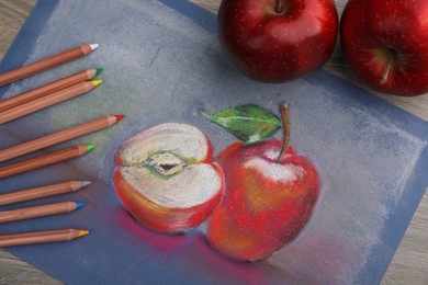 Beautiful drawing of red apples and color pencils on wooden table, flat lay