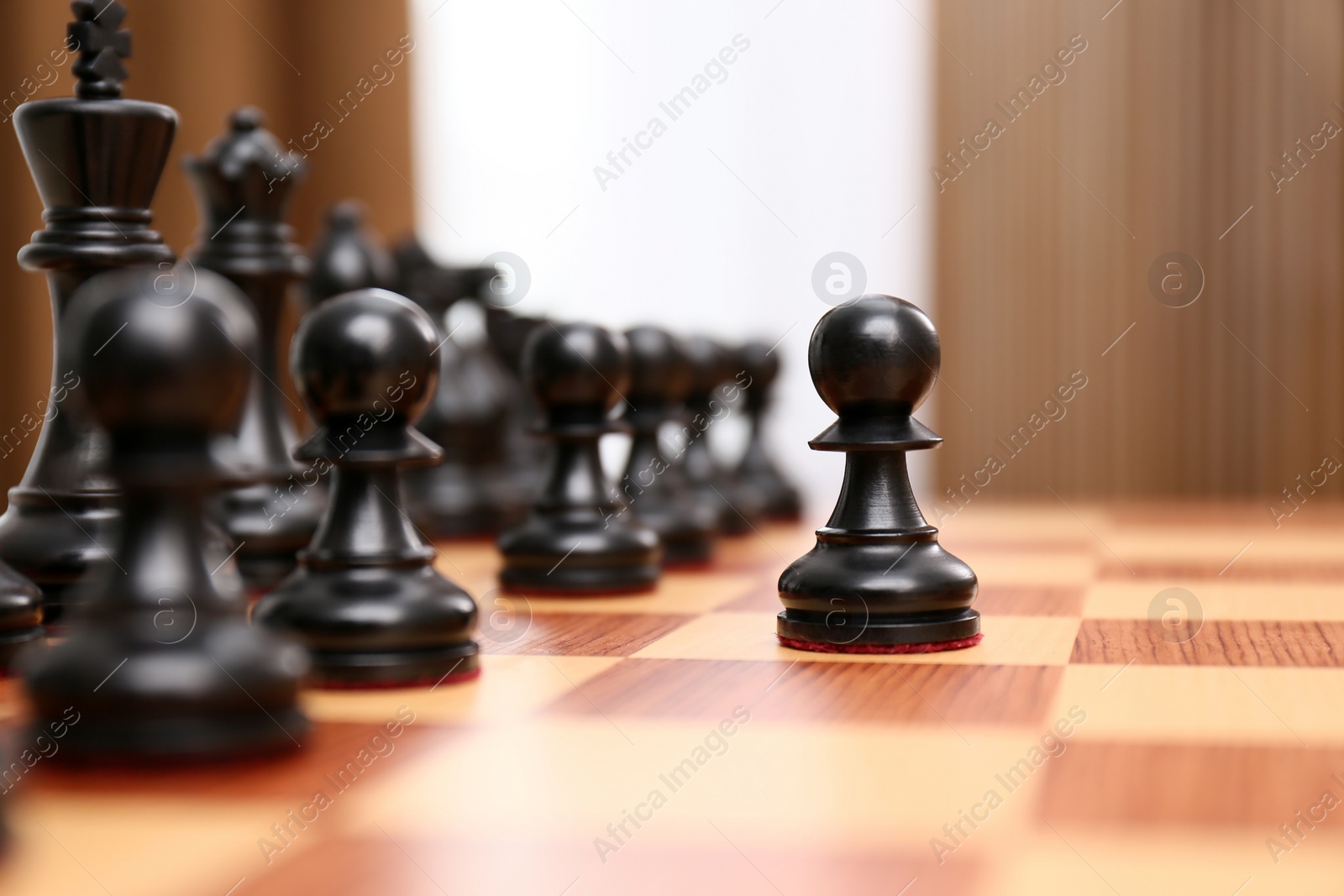 Photo of Pawn piece leading others on chessboard indoors
