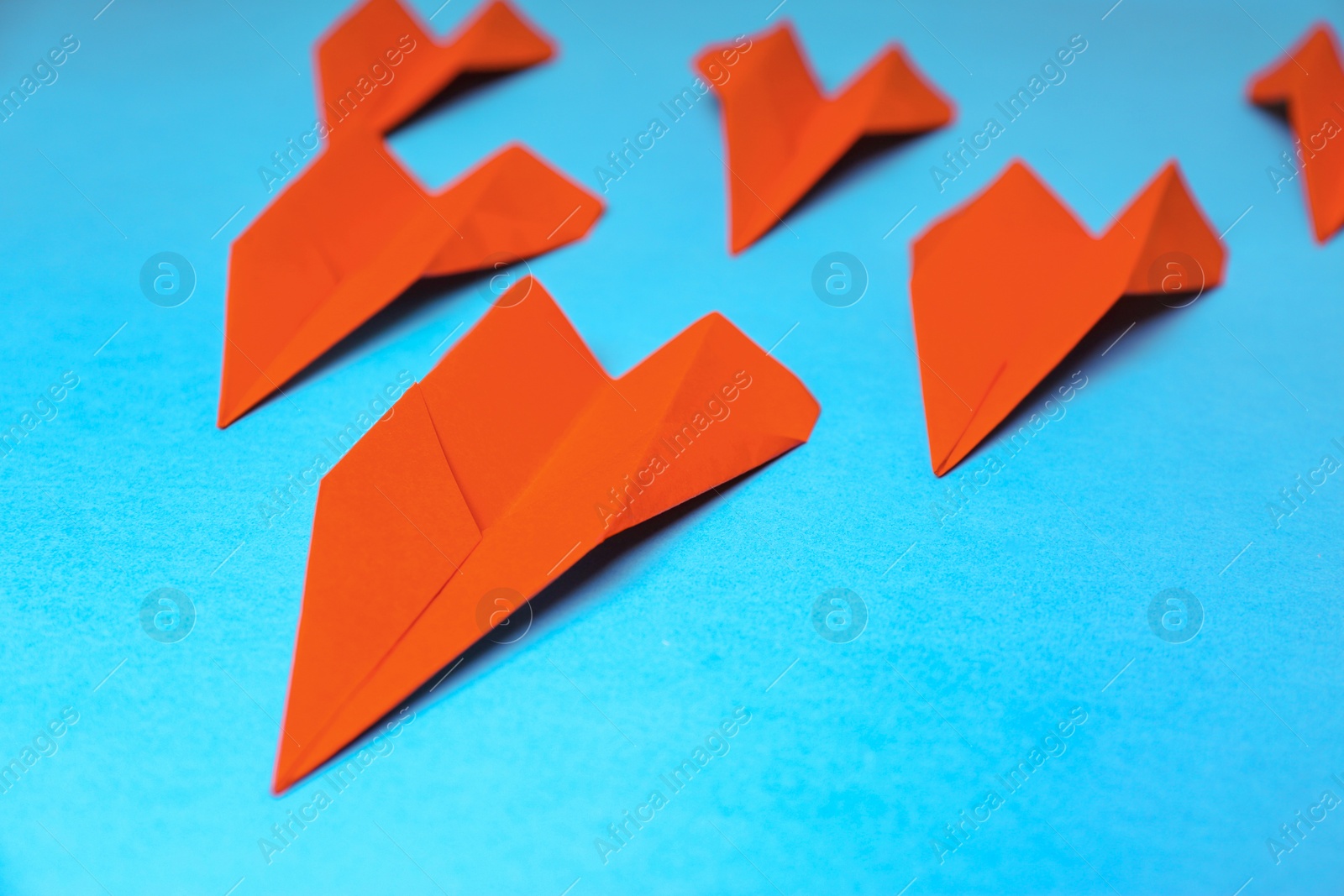 Photo of Many red paper planes on light blue background, closeup