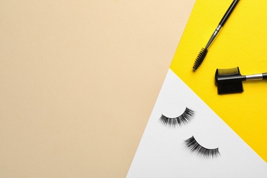 Photo of False eyelashes and brushes on color background, flat lay. Space for text