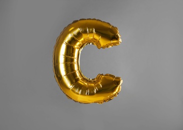 Golden letter C balloon on grey background