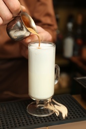 Photo of Barista adding coffee to steamed milk at counter, closeup view