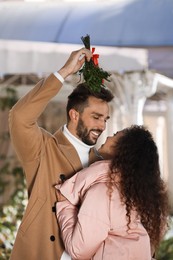 Photo of Happy couple under mistletoe bunch outdoors. Christmas tradition