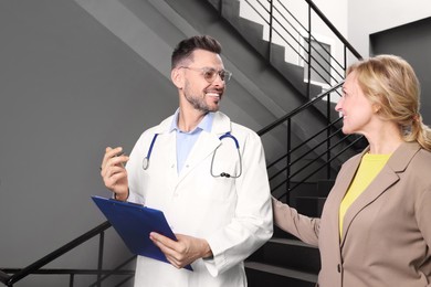 Photo of Happy doctor with clipboard and patient in clinic