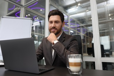 Photo of Man working on laptop at black desk in office