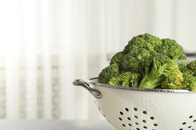 Raw green broccoli in colander on light background, closeup. Space for text