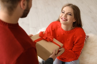 Photo of Happy young couple with Christmas gift box at home