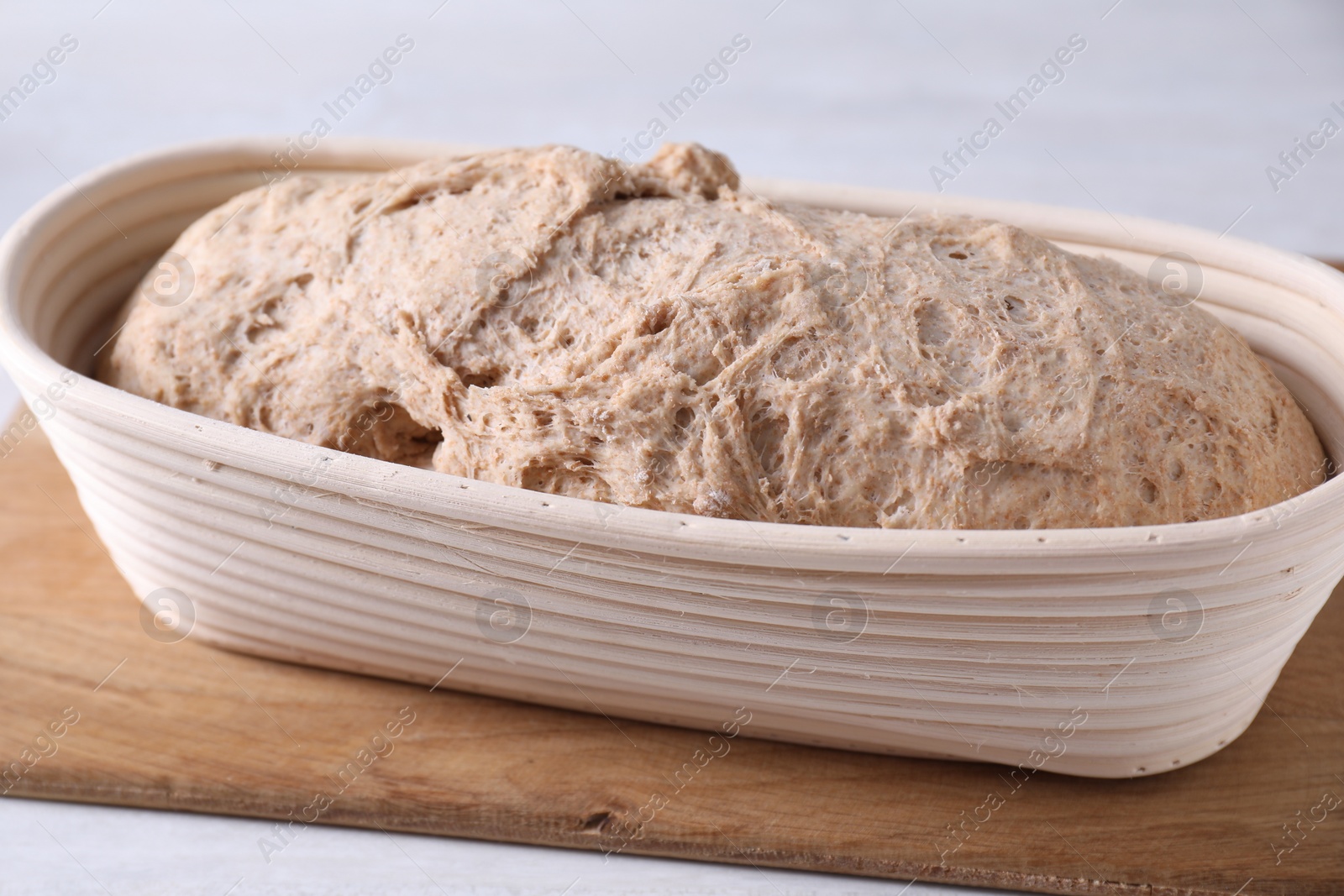 Photo of Fresh sourdough in proofing basket on light table, closeup