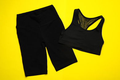 Photo of New black sportswear on yellow background, flat lay
