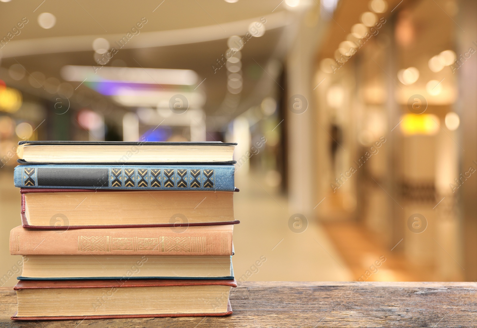 Image of Collection of different books on wooden table against blurred background, space for text