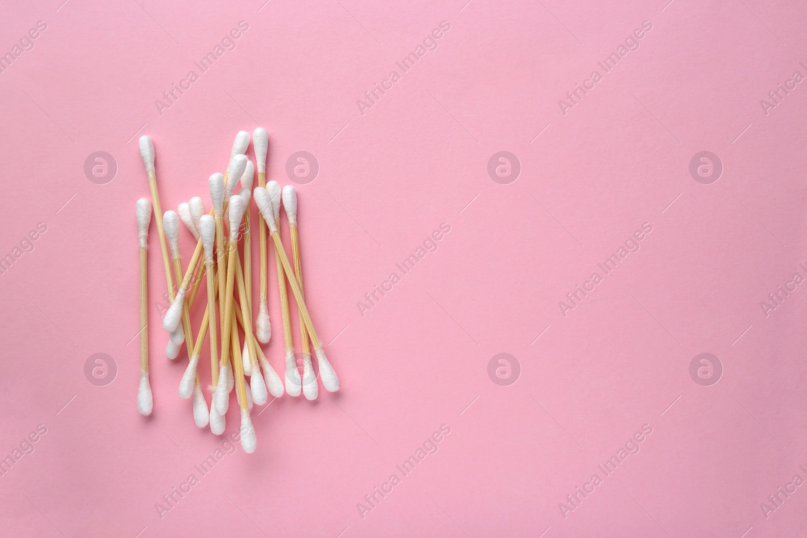 Photo of Heap of wooden cotton buds on pink background, flat lay. Space for text