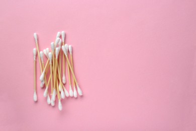 Photo of Heap of wooden cotton buds on pink background, flat lay. Space for text