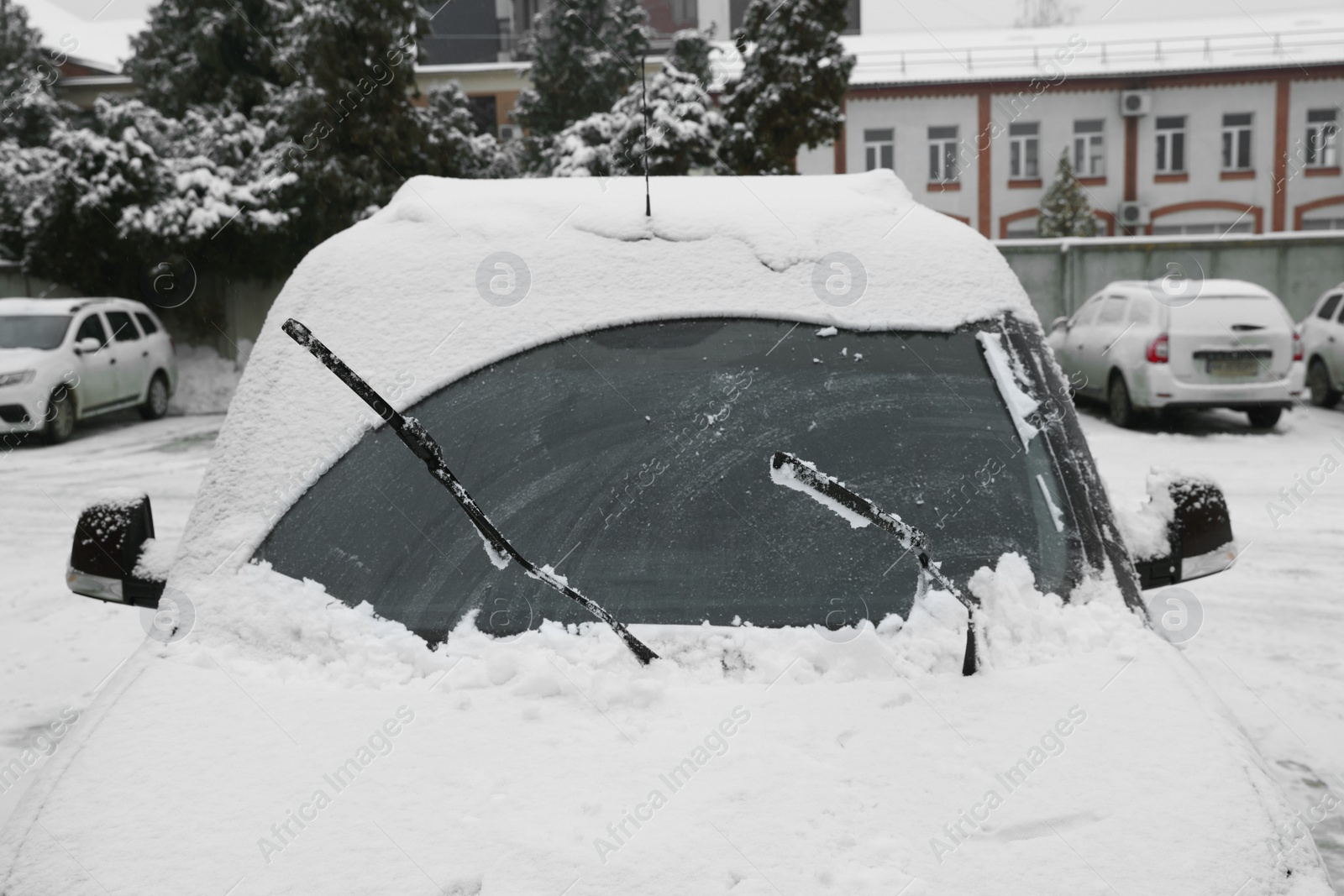 Photo of Car windshield with wiper blades cleaned from snow outdoors on winter day