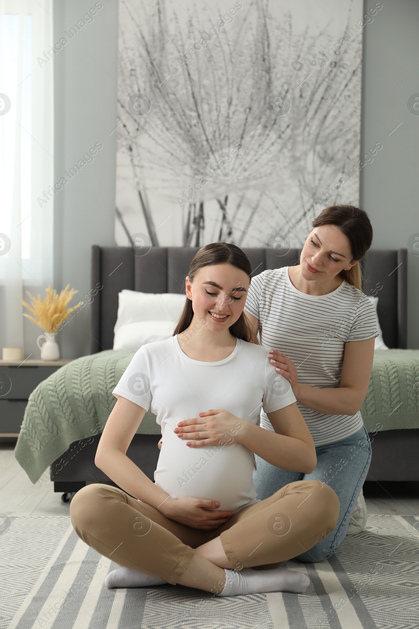 Photo of Doula massaging pregnant woman in bedroom. Preparation for child birth