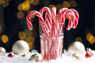 Photo of Many sweet candy canes in glass against blurred festive lights. Traditional Christmas treat