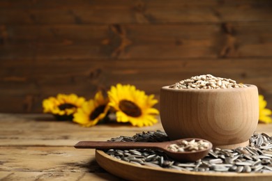 Photo of Raw sunflower seeds on wooden table. Space for text
