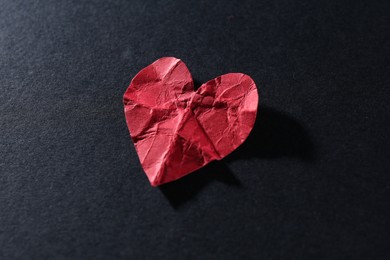 Photo of Red crumpled paper heart on black background, closeup. Breakup concept