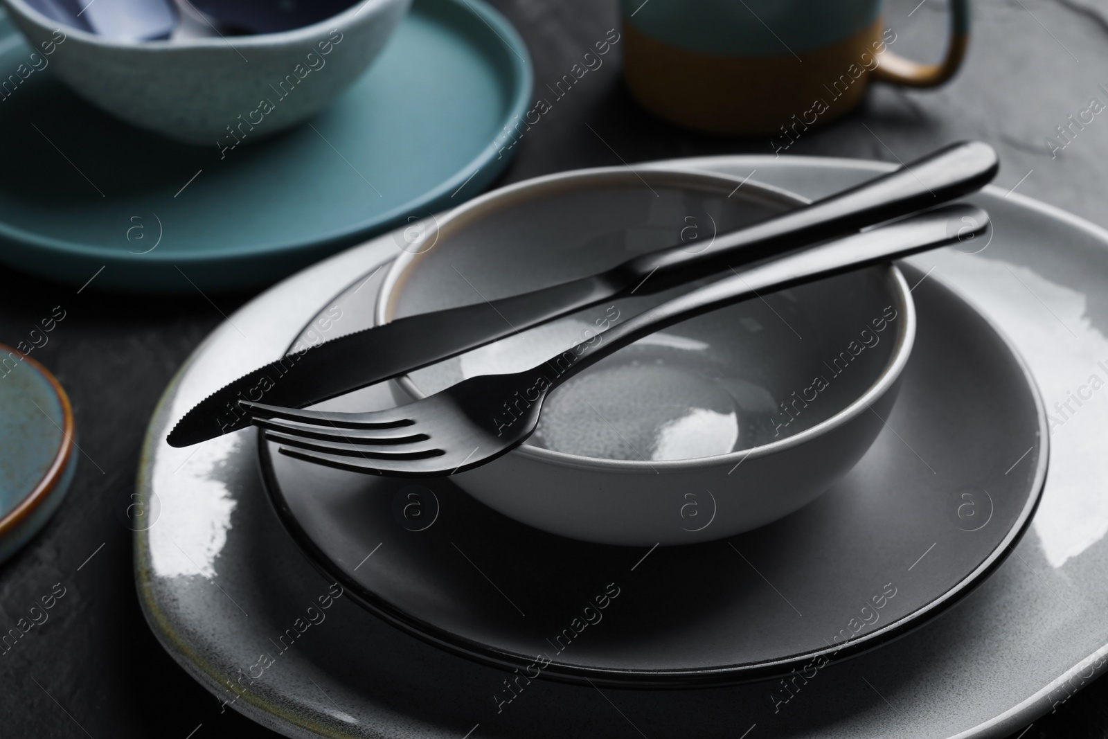 Photo of Set of clean tableware on black table, closeup