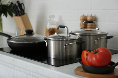 Saucepots and frying pan on induction stove in kitchen