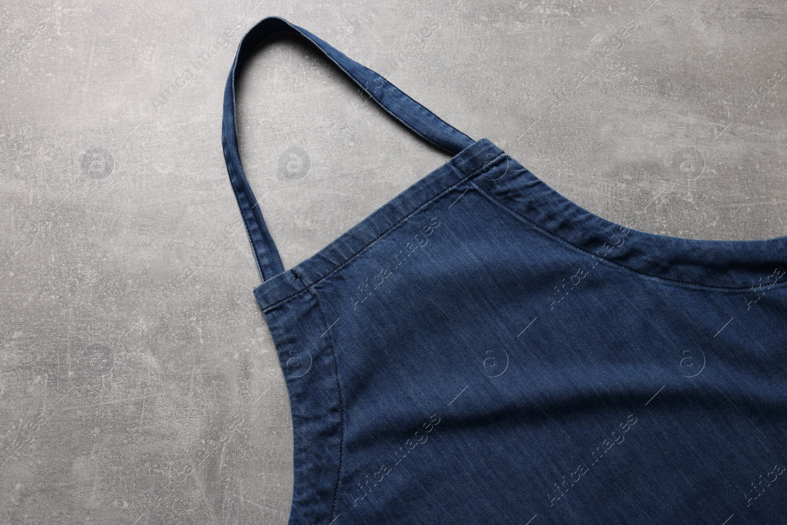 Photo of Stylish blue apron on grey table, top view. Mockup for design