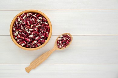 Bowl and spoon with dry kidney beans on white wooden table, flat lay. Space for text