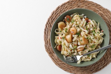 Delicious scallop pasta with spices in bowl served on white table, top view. Space for text