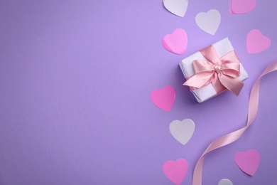 Photo of Gift box, ribbon and hearts on violet background, flat lay with space for text. Valentine's Day celebration