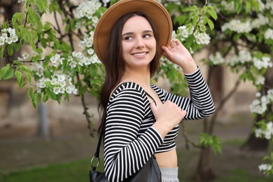 Beautiful woman in hat near blossoming tree on spring day