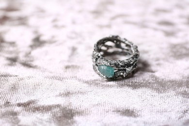 Photo of Beautiful silver ring with apatite gemstone on light fabric. Space for text