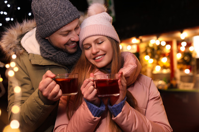 Happy couple with mulled wine at winter fair