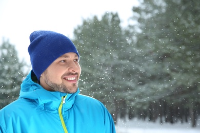 Photo of Portrait of happy man in snowy forest. Space for text