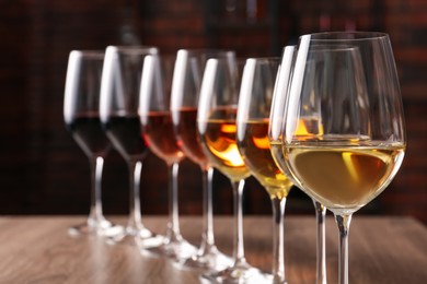 Different tasty wines in glasses on wooden table