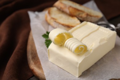 Tasty butter and slices of bread on wooden board, closeup. Space for text