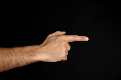 Photo of Man pointing at something on black background, closeup. Finger gesture