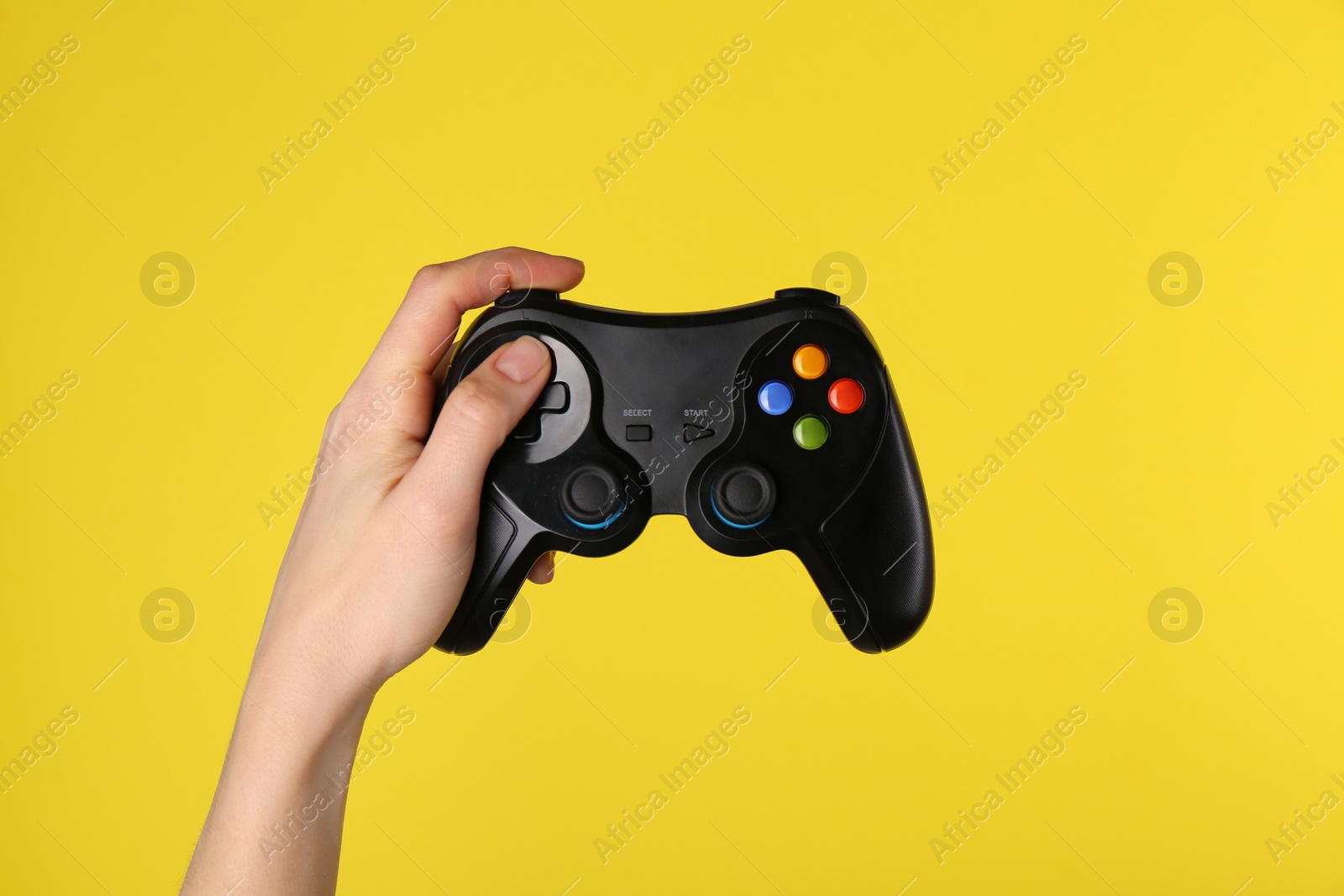 Photo of Woman using game controller on yellow background, closeup