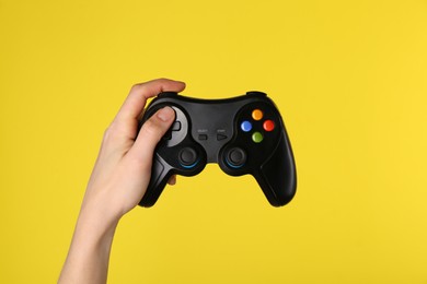 Photo of Woman using game controller on yellow background, closeup